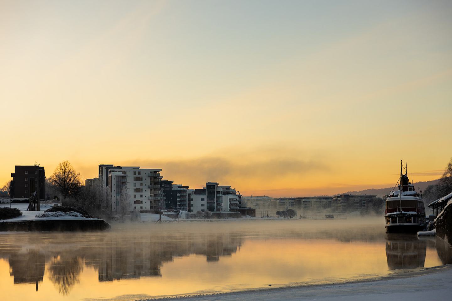 Hjellevannet en frostklar morgen, med frostrøyk over vannet og byen i motlys