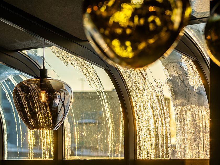 Store pendellamper av glass i vinterhagen på Strøm, med buede, isete vinduer og stoler bak