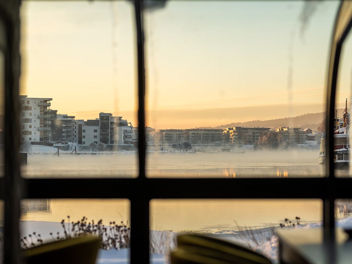 Utsikt over vannet i soloppgang gjennom vinduskarmene i vinterhagen